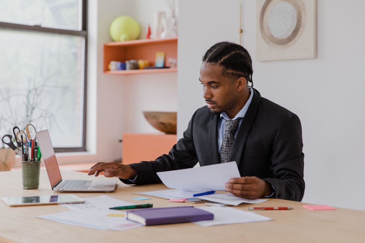 Business owner at his desk reviewing paperwork next to a laptop